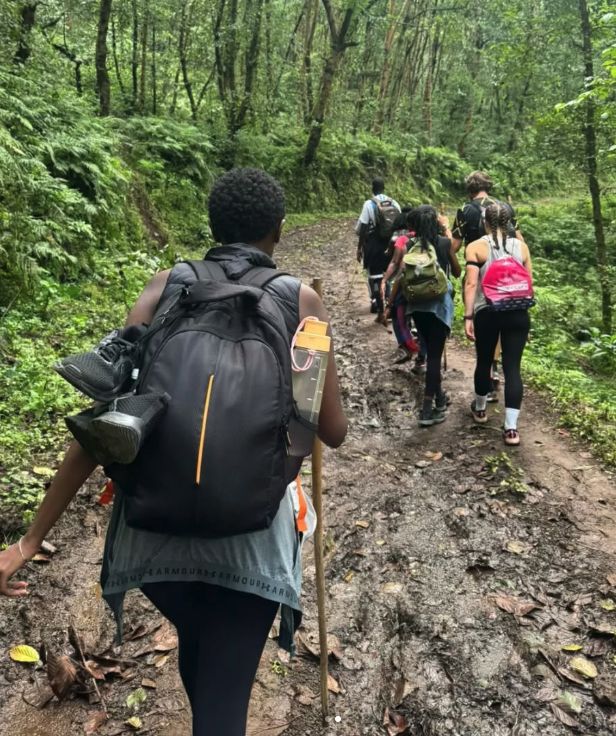 Trekkers with backpacks walking a muddy forest track